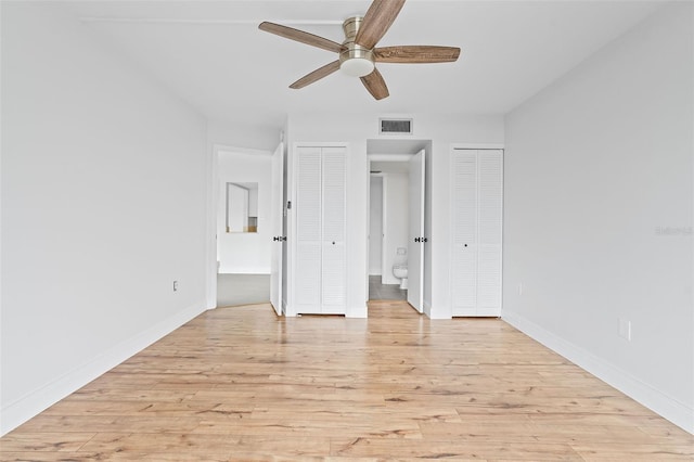 unfurnished bedroom featuring ceiling fan, ensuite bath, and light wood-type flooring