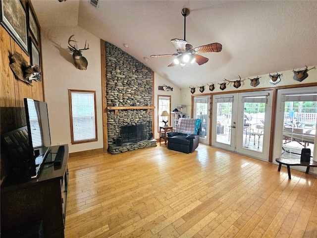 living room featuring a fireplace, a healthy amount of sunlight, light wood-type flooring, and ceiling fan