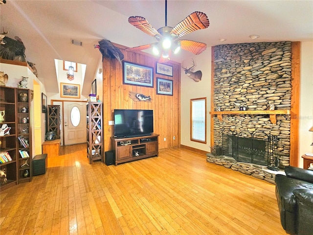 living room featuring hardwood / wood-style floors, ceiling fan, high vaulted ceiling, a fireplace, and wooden walls