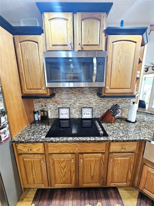 kitchen with light hardwood / wood-style floors, decorative backsplash, and dark stone counters