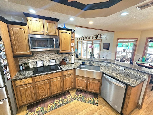 kitchen featuring kitchen peninsula, crown molding, light wood-type flooring, appliances with stainless steel finishes, and a textured ceiling