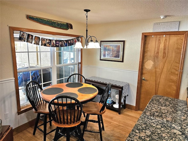 dining space featuring a notable chandelier, a textured ceiling, and light wood-type flooring