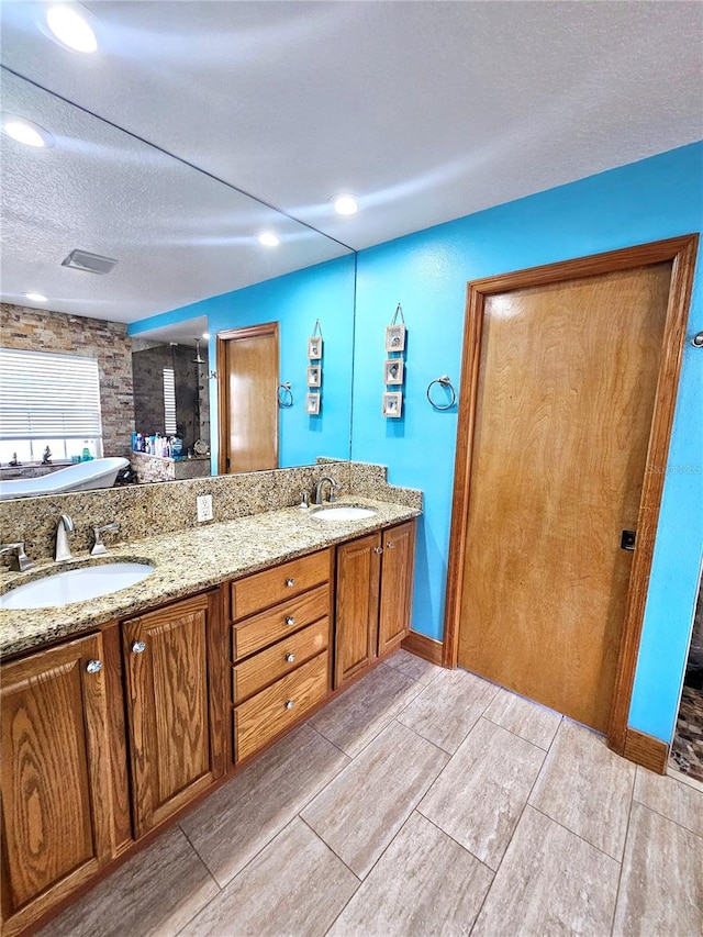 bathroom featuring vanity, a textured ceiling, and a bathing tub