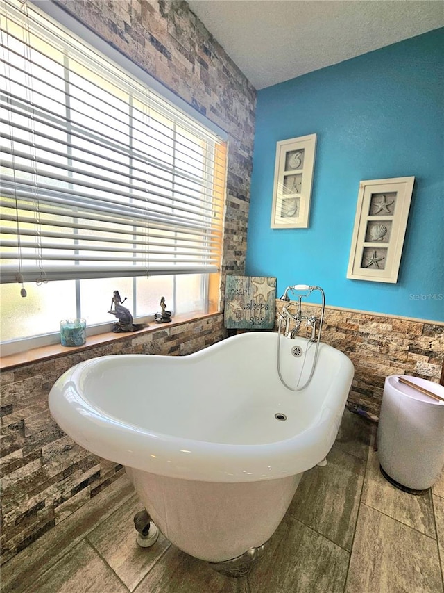 bathroom featuring a tub, tile walls, and a textured ceiling