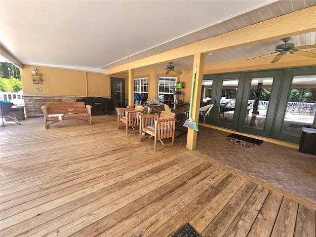 wooden terrace featuring french doors, ceiling fan, and an outdoor living space