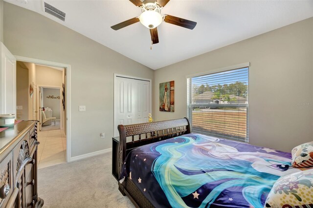 bedroom featuring a closet, ceiling fan, light carpet, and lofted ceiling