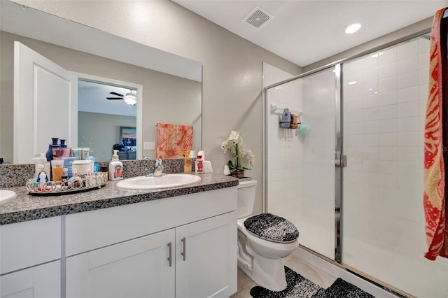 bathroom with vanity, a shower with shower door, toilet, and ceiling fan