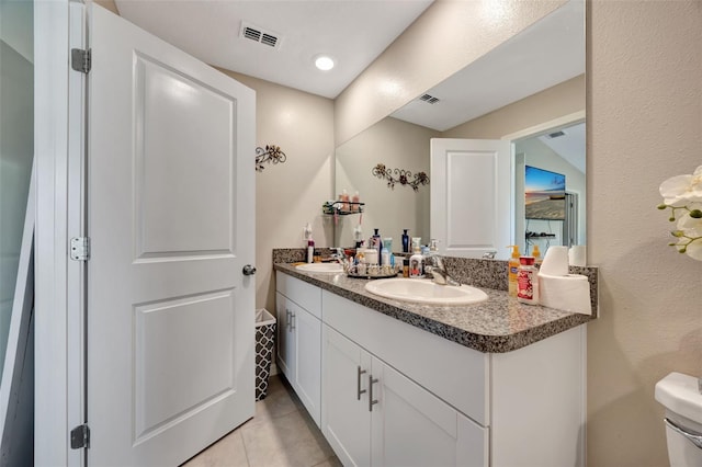 bathroom with toilet, vanity, and tile patterned floors