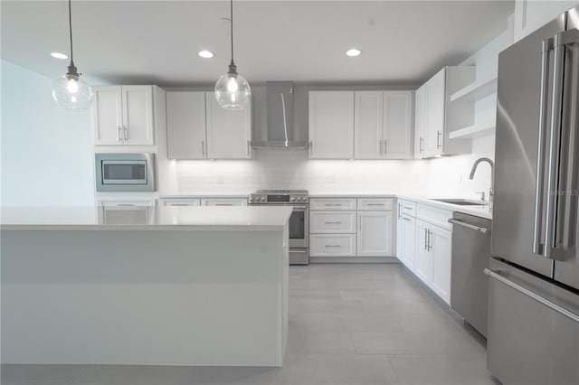 kitchen with wall chimney exhaust hood, appliances with stainless steel finishes, pendant lighting, and white cabinets