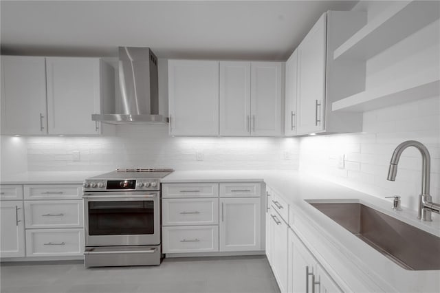 kitchen featuring wall chimney range hood, backsplash, sink, electric range, and white cabinets