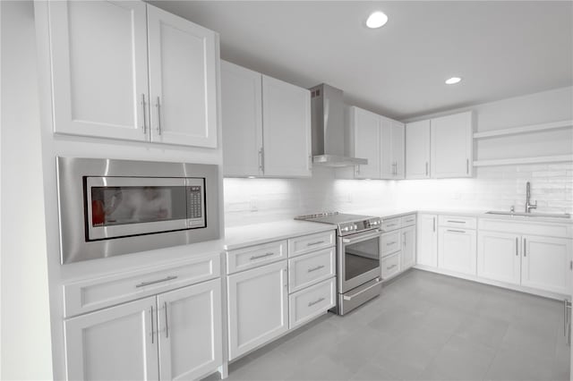 kitchen with tasteful backsplash, wall chimney range hood, appliances with stainless steel finishes, sink, and white cabinetry