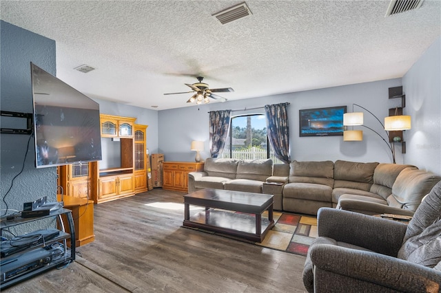 living room with a textured ceiling, dark wood-type flooring, and ceiling fan