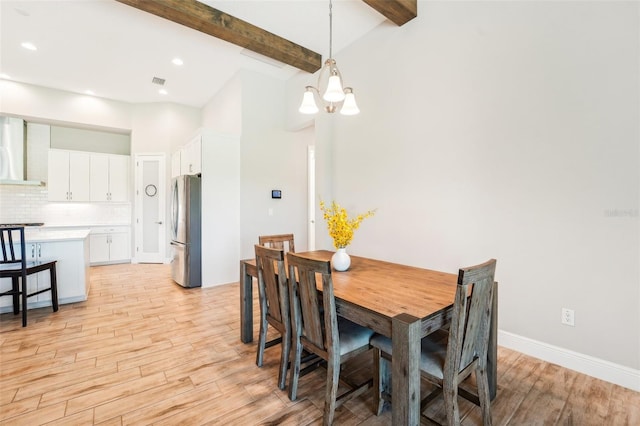 dining space with beam ceiling, a chandelier, and light hardwood / wood-style flooring