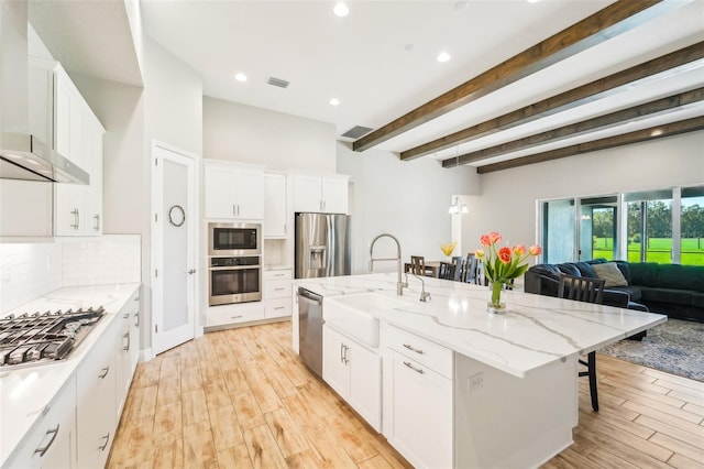 kitchen featuring sink, a kitchen breakfast bar, white cabinetry, stainless steel appliances, and a kitchen island with sink