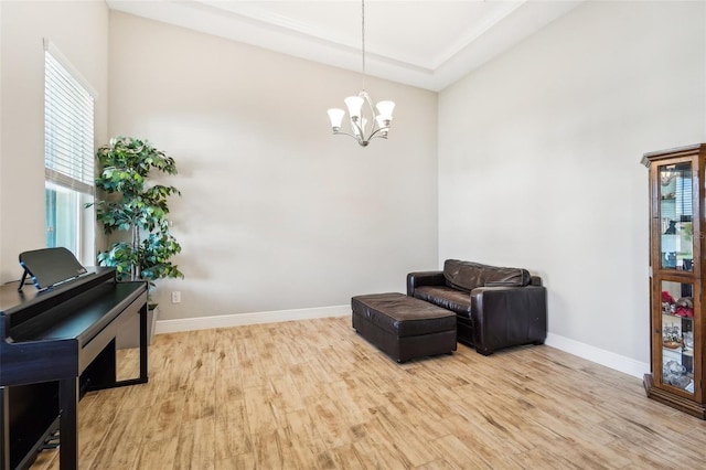 living area featuring a towering ceiling, an inviting chandelier, and hardwood / wood-style floors