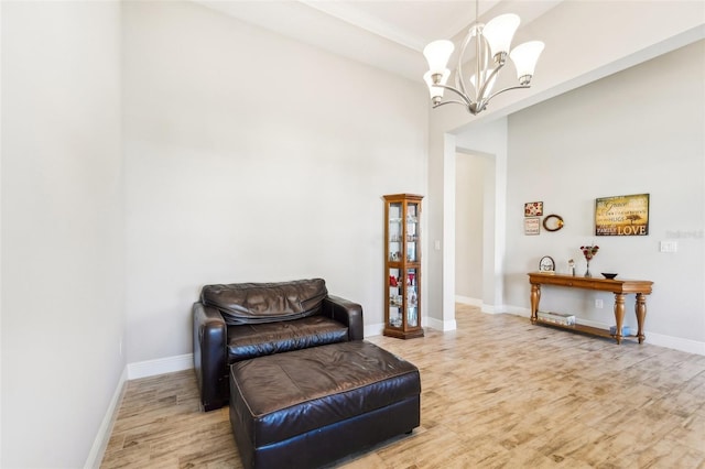 living area featuring light hardwood / wood-style floors, a notable chandelier, and a high ceiling