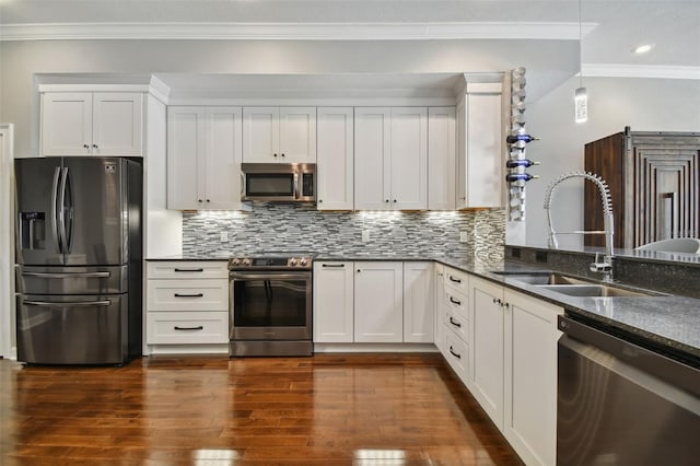 kitchen featuring appliances with stainless steel finishes, white cabinetry, dark stone countertops, dark hardwood / wood-style floors, and sink