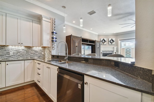 kitchen with sink, dark stone counters, pendant lighting, stainless steel dishwasher, and white cabinets