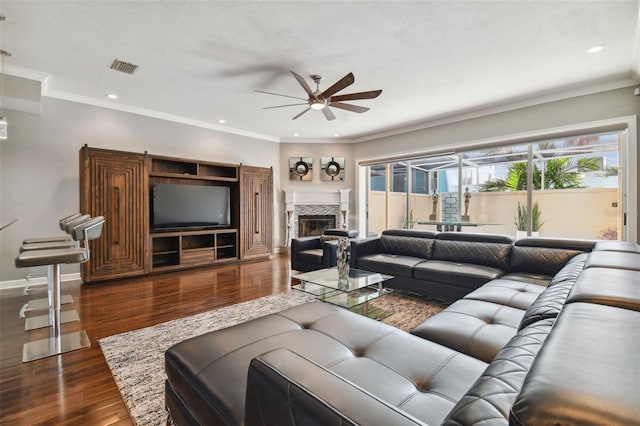 living room featuring ornamental molding, dark hardwood / wood-style floors, and a stone fireplace