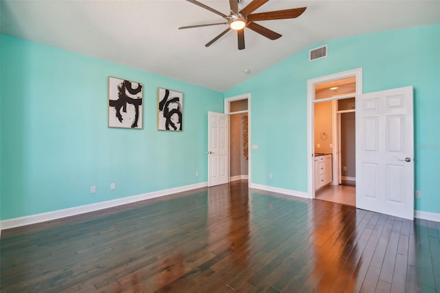 unfurnished bedroom with connected bathroom, dark wood-type flooring, lofted ceiling, and ceiling fan