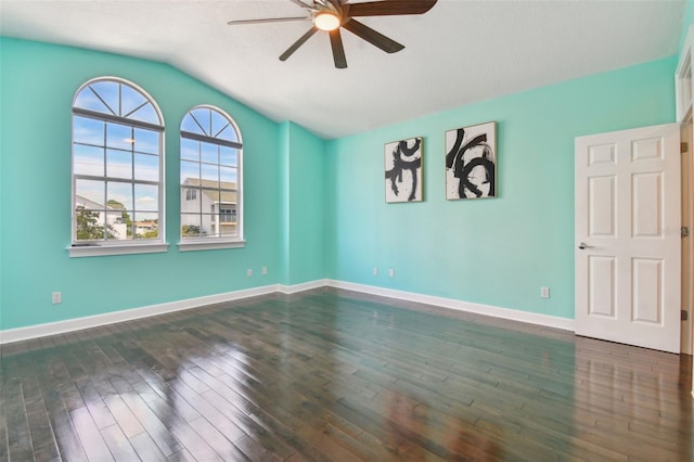 empty room featuring dark wood-type flooring, vaulted ceiling, a textured ceiling, and ceiling fan