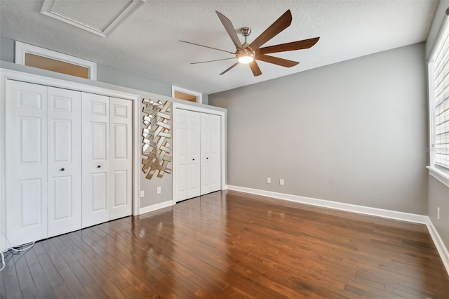 unfurnished bedroom featuring dark wood-type flooring, a textured ceiling, and multiple windows