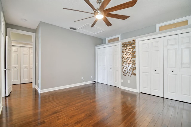 unfurnished bedroom with dark hardwood / wood-style floors, two closets, and ceiling fan