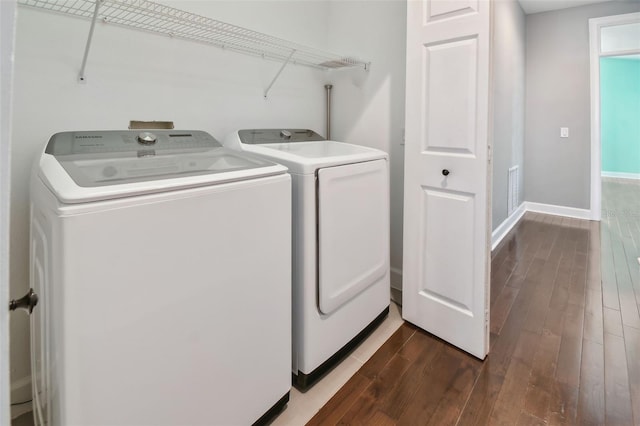 clothes washing area featuring dark wood-type flooring and washing machine and dryer