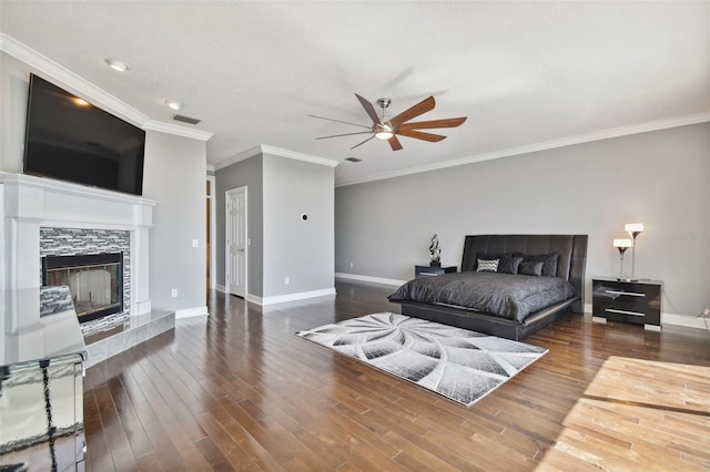 bedroom featuring ceiling fan, ornamental molding, a tile fireplace, and dark hardwood / wood-style floors