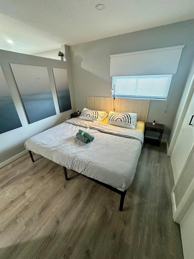 bedroom with dark hardwood / wood-style flooring and a textured ceiling