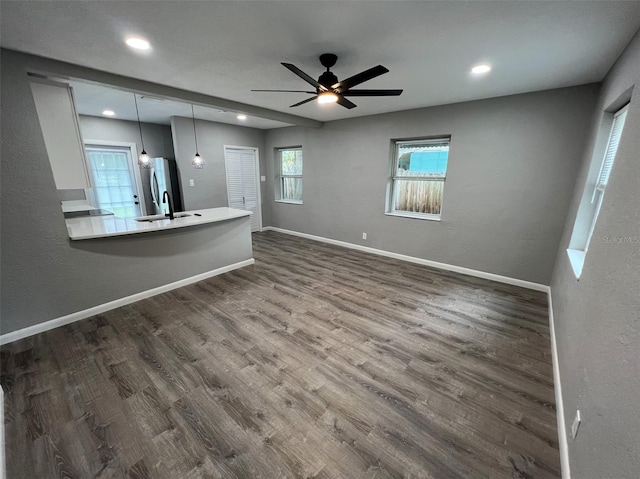 unfurnished living room featuring hardwood / wood-style flooring, ceiling fan, and sink