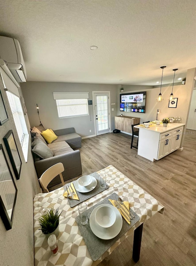 living room with a textured ceiling, light hardwood / wood-style floors, and a wall mounted air conditioner