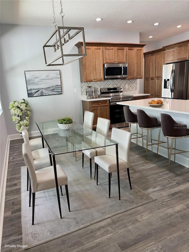 kitchen featuring a kitchen breakfast bar, tasteful backsplash, stainless steel appliances, dark wood-type flooring, and decorative light fixtures