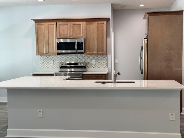 kitchen featuring sink, stainless steel appliances, tasteful backsplash, dark hardwood / wood-style flooring, and a kitchen island with sink