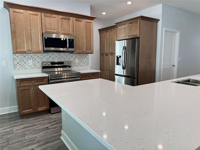 kitchen featuring sink, light stone countertops, appliances with stainless steel finishes, tasteful backsplash, and dark hardwood / wood-style flooring