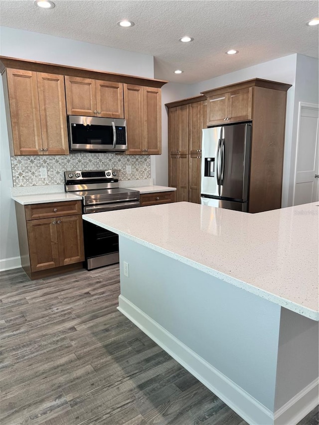 kitchen with light stone countertops, backsplash, and stainless steel appliances