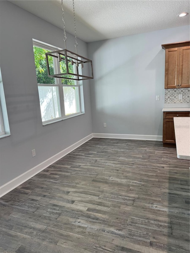 unfurnished dining area with plenty of natural light, dark hardwood / wood-style floors, and a textured ceiling