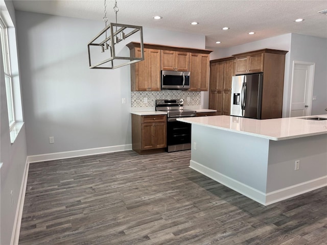 kitchen with dark wood-type flooring, decorative backsplash, a textured ceiling, appliances with stainless steel finishes, and decorative light fixtures