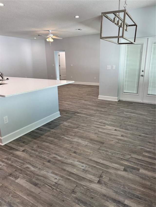 interior space featuring a textured ceiling, french doors, dark hardwood / wood-style floors, and ceiling fan with notable chandelier