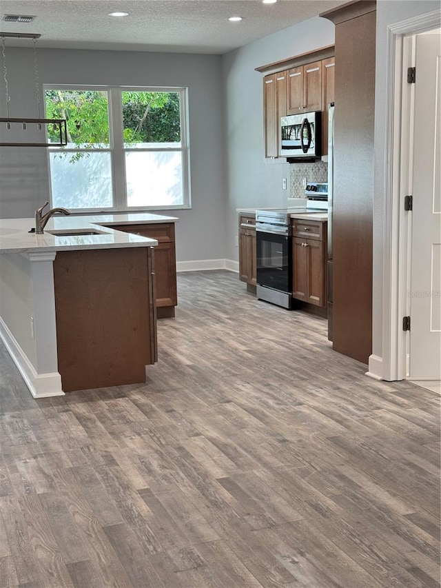 kitchen with decorative backsplash, dark hardwood / wood-style flooring, a textured ceiling, stainless steel appliances, and sink