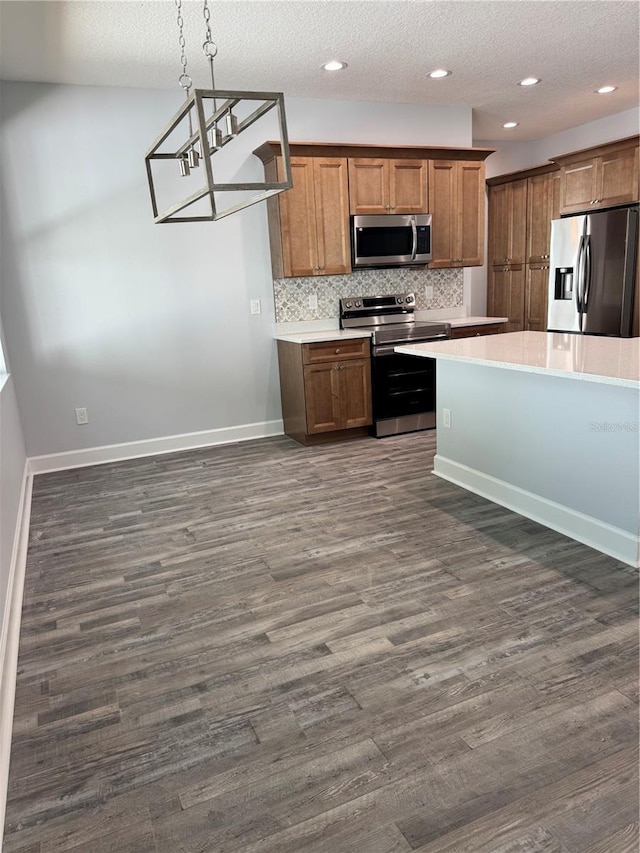 kitchen with backsplash, dark wood-type flooring, hanging light fixtures, a textured ceiling, and stainless steel appliances