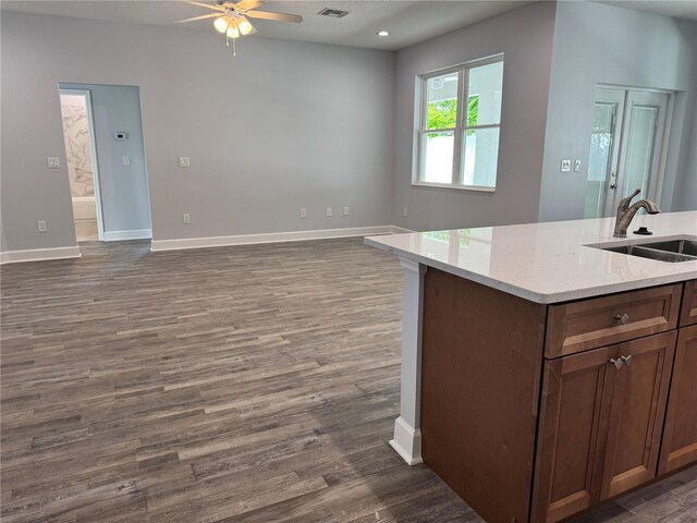 kitchen with light stone counters, ceiling fan, dark wood-type flooring, and sink