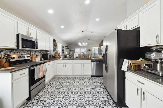 kitchen featuring appliances with stainless steel finishes, lofted ceiling, white cabinets, and kitchen peninsula