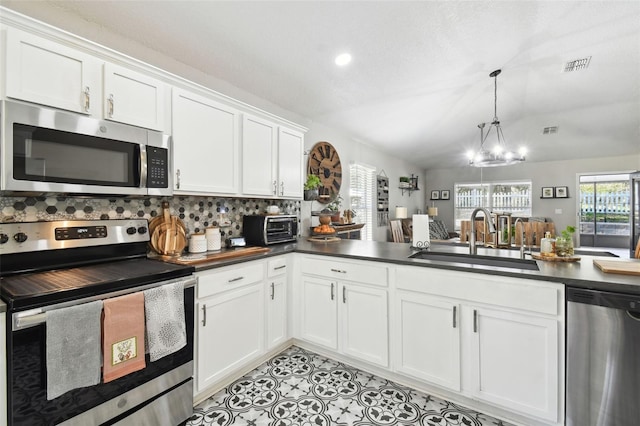 kitchen featuring sink, backsplash, stainless steel appliances, lofted ceiling, and an inviting chandelier