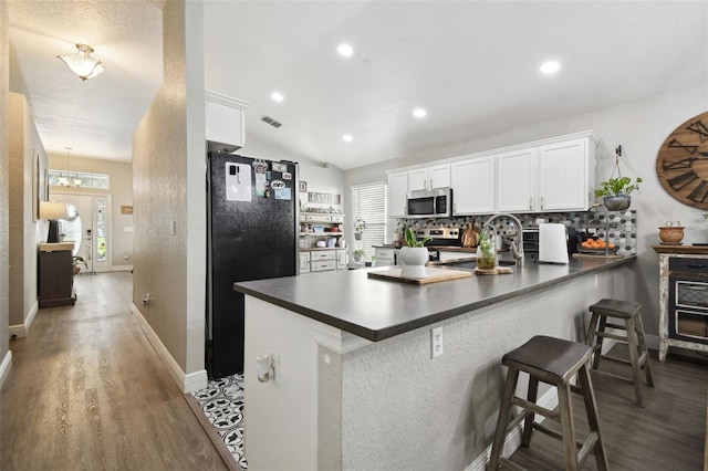 kitchen with white cabinetry, stainless steel appliances, kitchen peninsula, and a healthy amount of sunlight