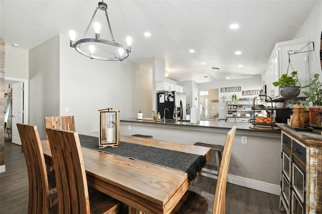 dining space featuring dark wood-type flooring and an inviting chandelier