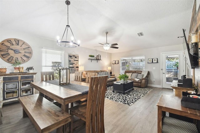 dining space featuring hardwood / wood-style floors, a textured ceiling, and ceiling fan with notable chandelier