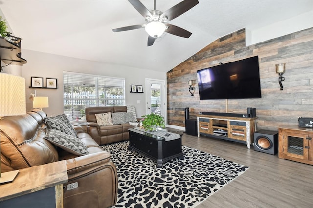 living room with hardwood / wood-style floors, vaulted ceiling, ceiling fan, and wood walls