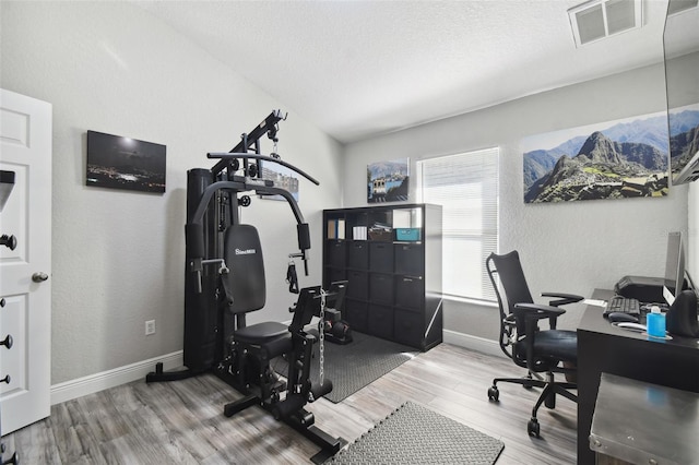 home office with light hardwood / wood-style flooring and a textured ceiling