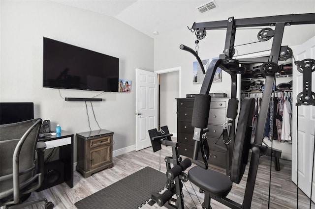 exercise room with lofted ceiling and light hardwood / wood-style floors